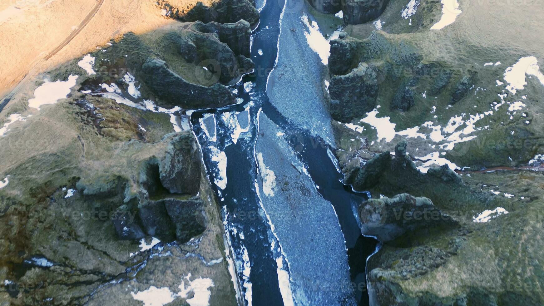 Drönare skott av isländsk kanjon med vatten ström och snöig bergen formning skön landskap. majestätisk fjadrargljufur kanjon med flod i Island, naturlig arktisk landskap. långsam rörelse. foto