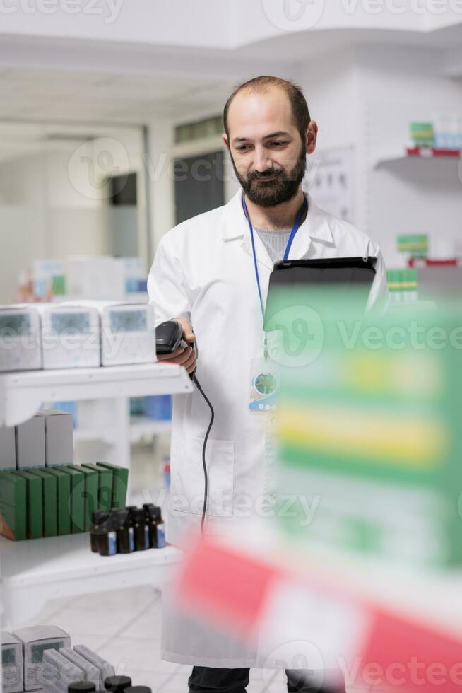 porträtt av apotekare kontroll medicin lista på läsplatta dator medan läser in piller paket använder sig av Lagra scanner i apotek. apotek arbetstagare är ansvarig för organisering och märkning de läkemedel foto