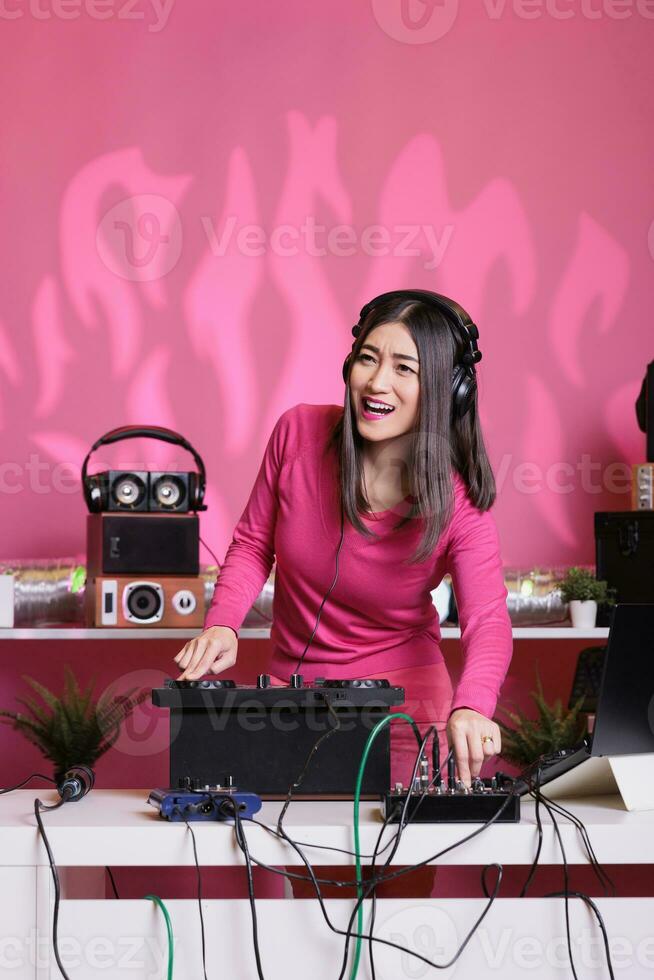 musiker blandning eletronic ljud med techno använder sig av professionell skivspelare, har roligt i studio över rosa bakgrund. konstnär utför låt med elektronik Utrustning och audio instrument foto