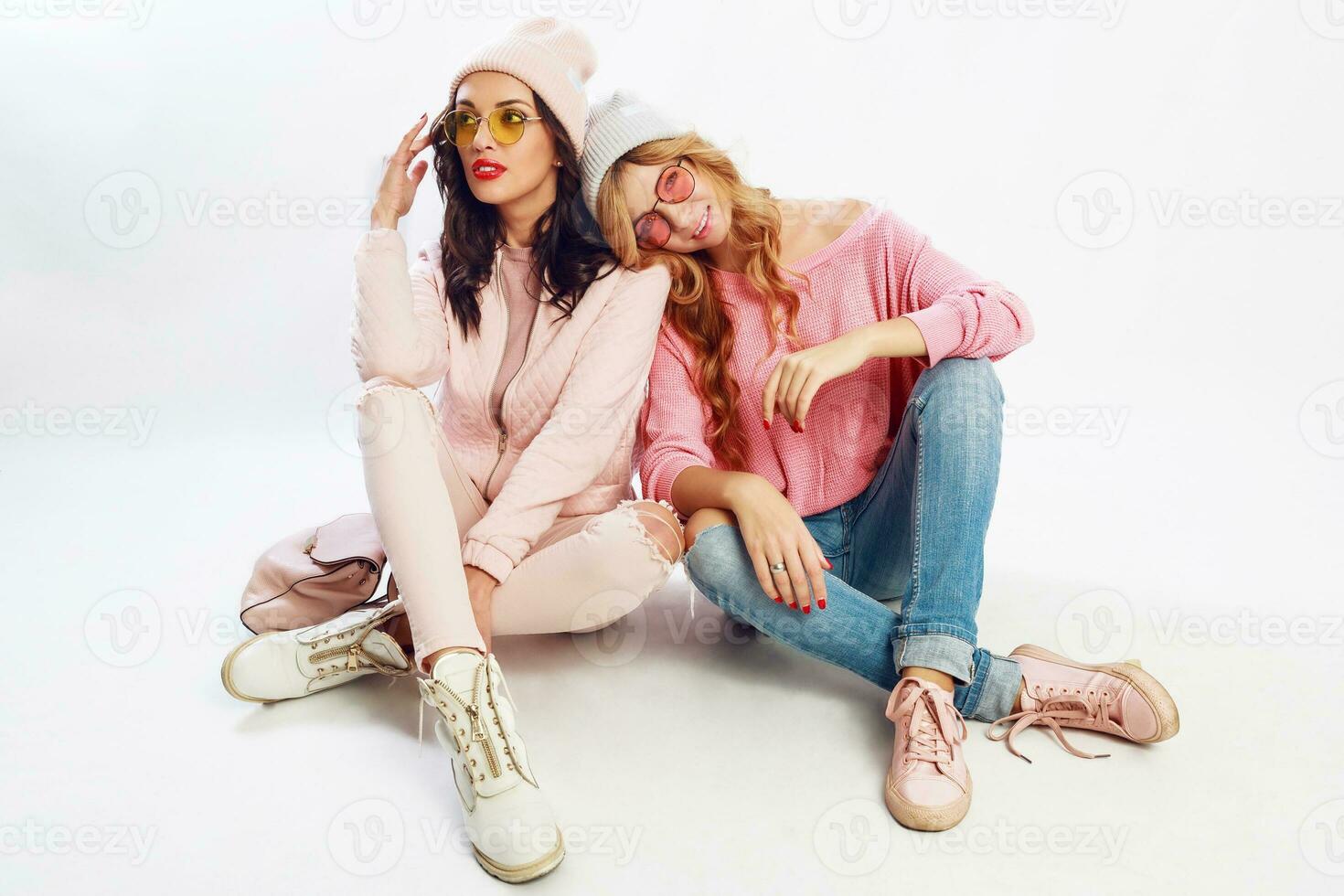 två trött vänner kylning på vit golv i studio. söt rosa utrusta. eleganta skor. foto