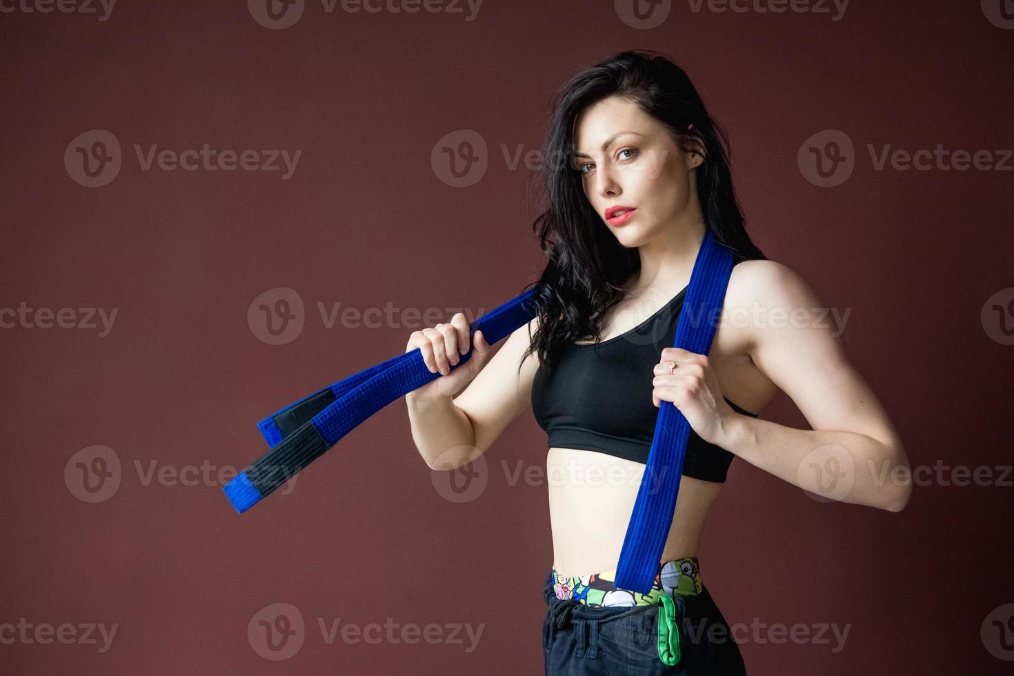 vacker atletisk kvinna med blått bälte på väggen bakgrund foto