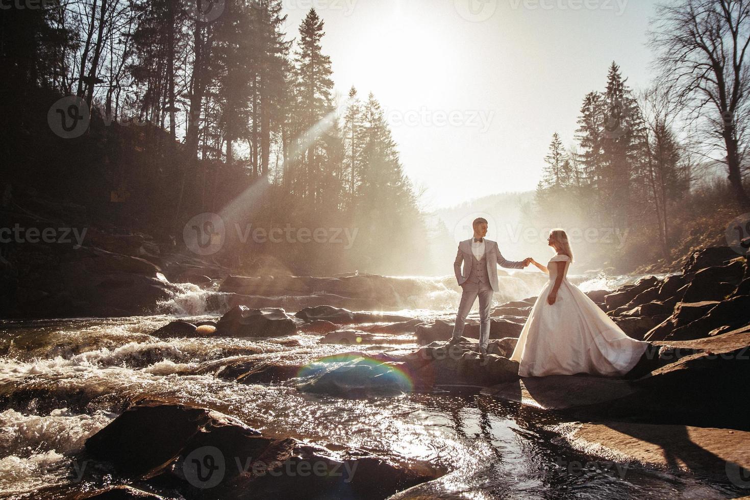 bröllopsparet håller händer på floder bakgrund i solnedgångarna foto