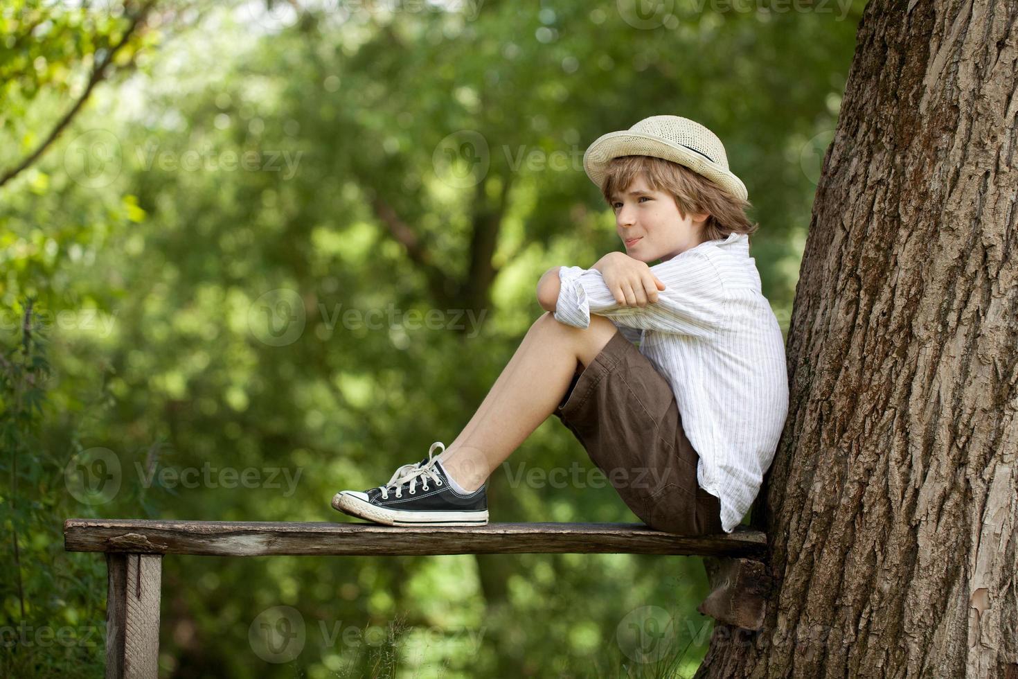 pojken sitter på en bänk foto