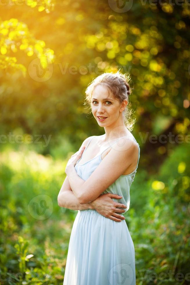 ung kvinna i en blå klänning i en sommar trädgård foto