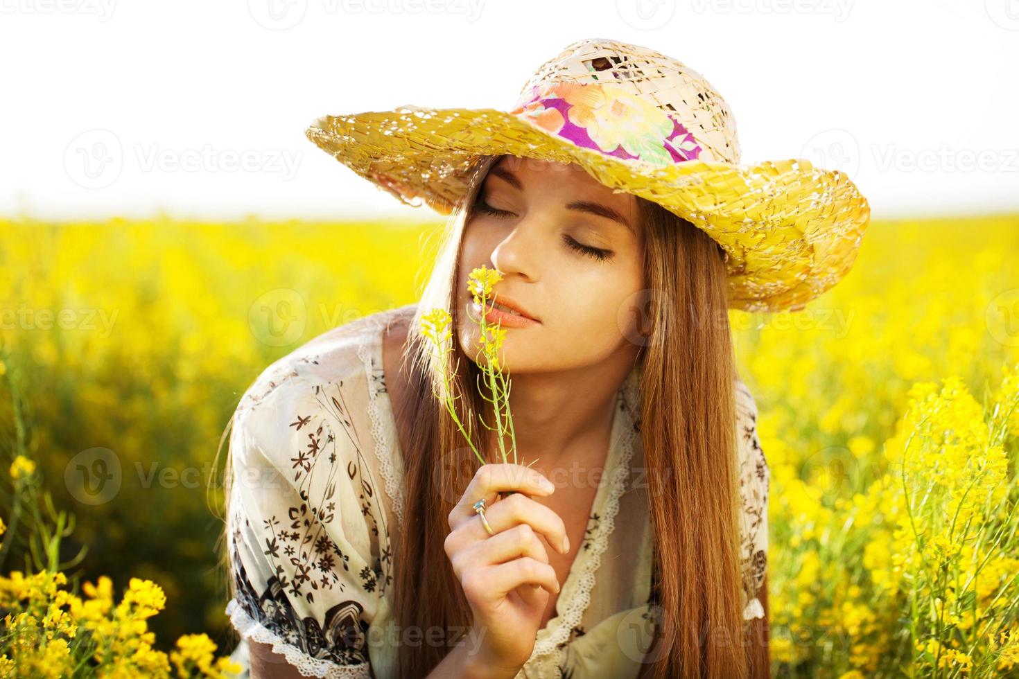 glad tjej tycker om lukten av en blomma foto