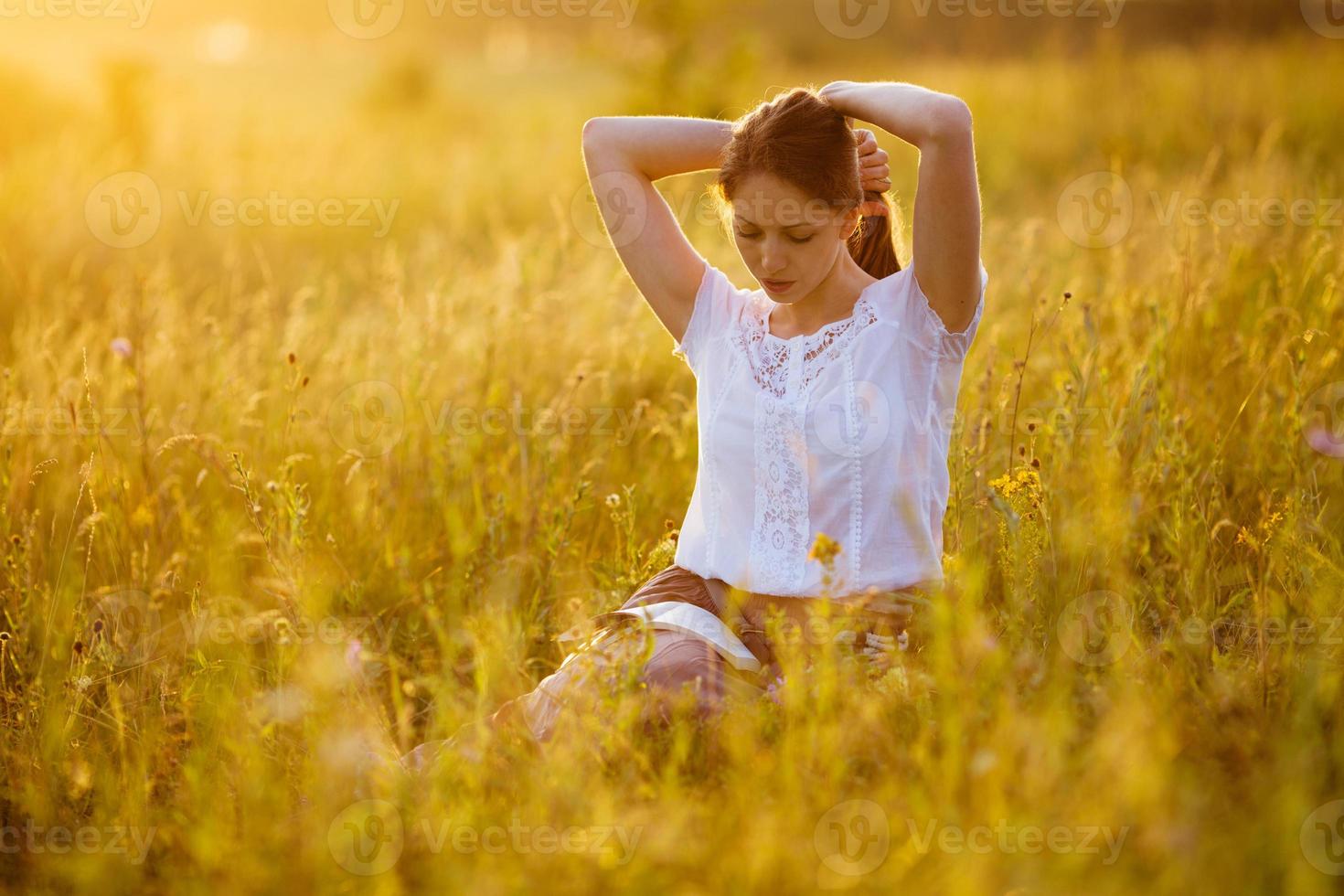 kvinna sitter på gräset och läser en bok foto