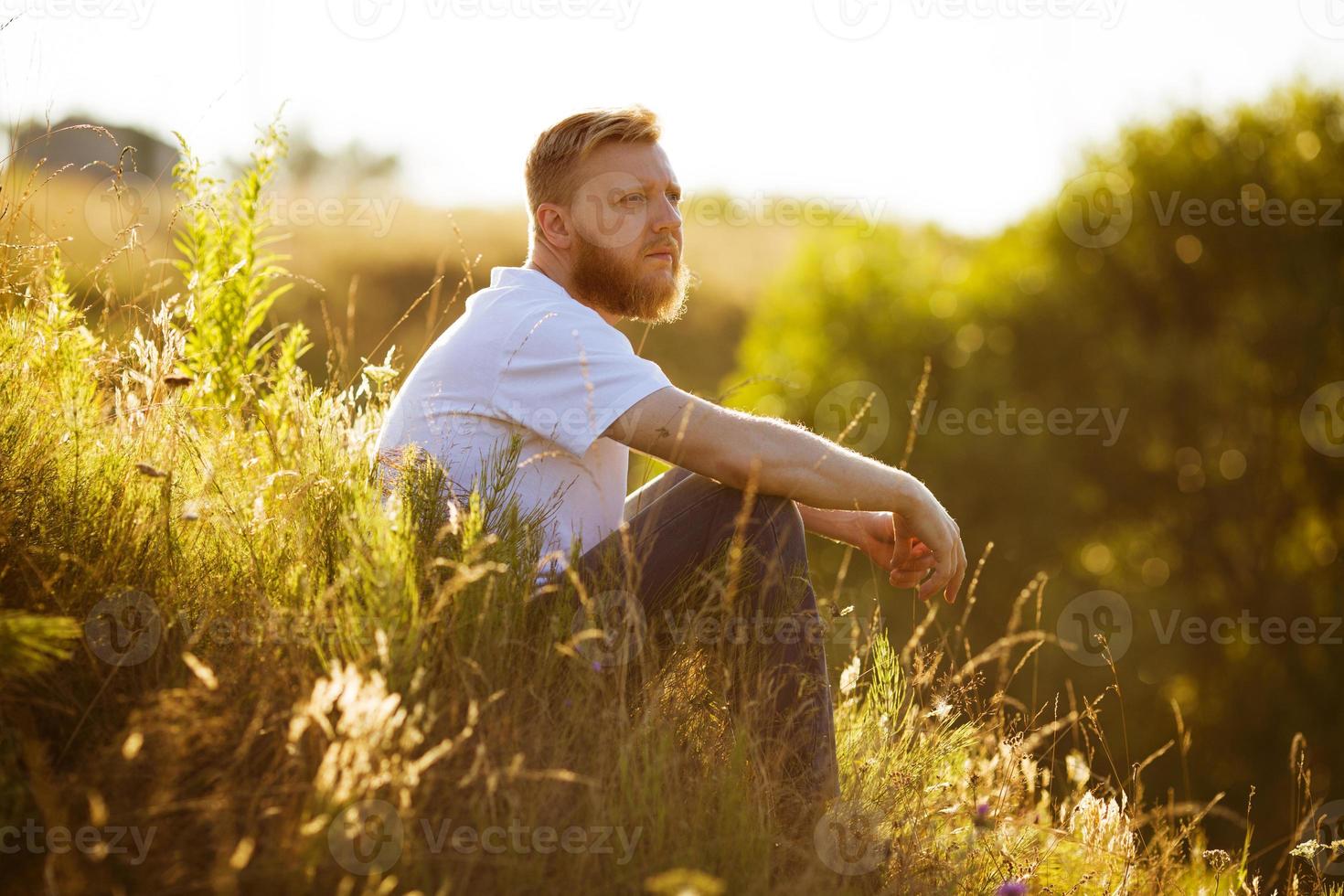 man sitter på gräset på kvällen foto