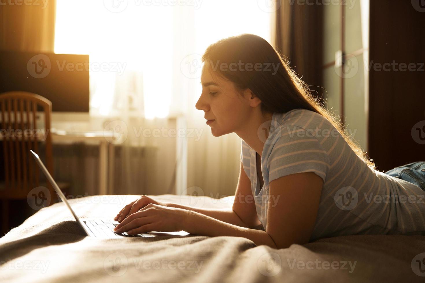 flicka ligger och skriver på en bärbar dator foto