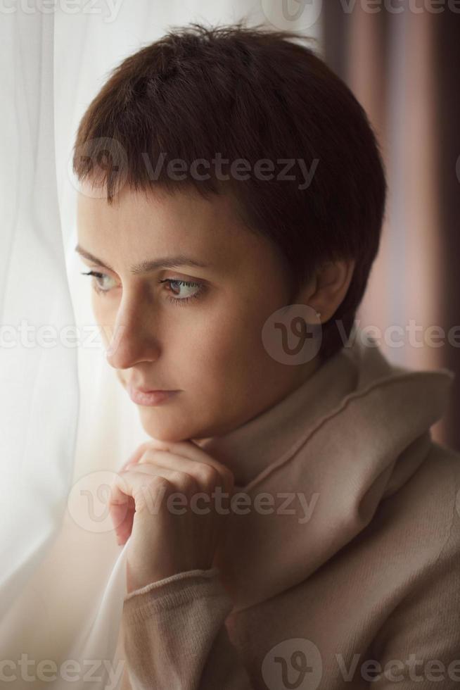 tankeväckande kvinna som står vid fönstret foto