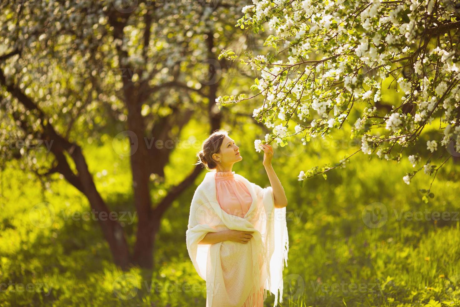 glad ung kvinna som luktar ett blommaäpple foto