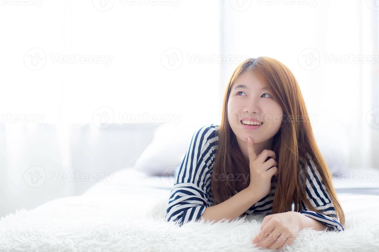 ung asiatisk kvinna som ligger och ler medan hon vaknar. foto
