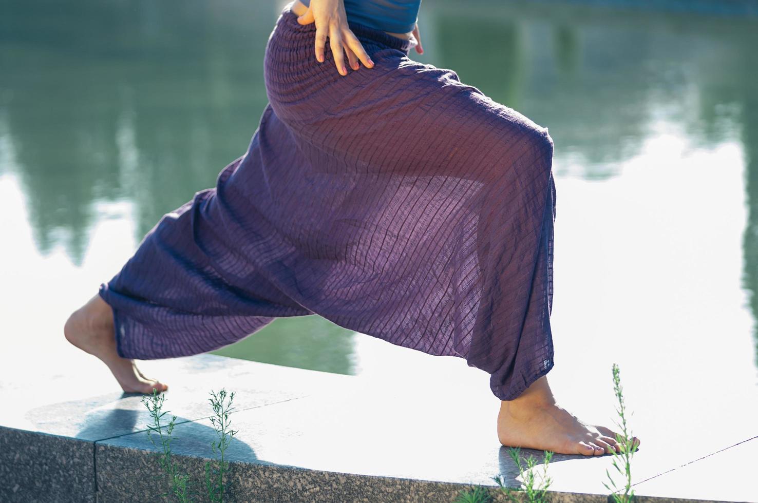 attraktiv kvinna i lila byxor som utövar yoga asana utomhus foto