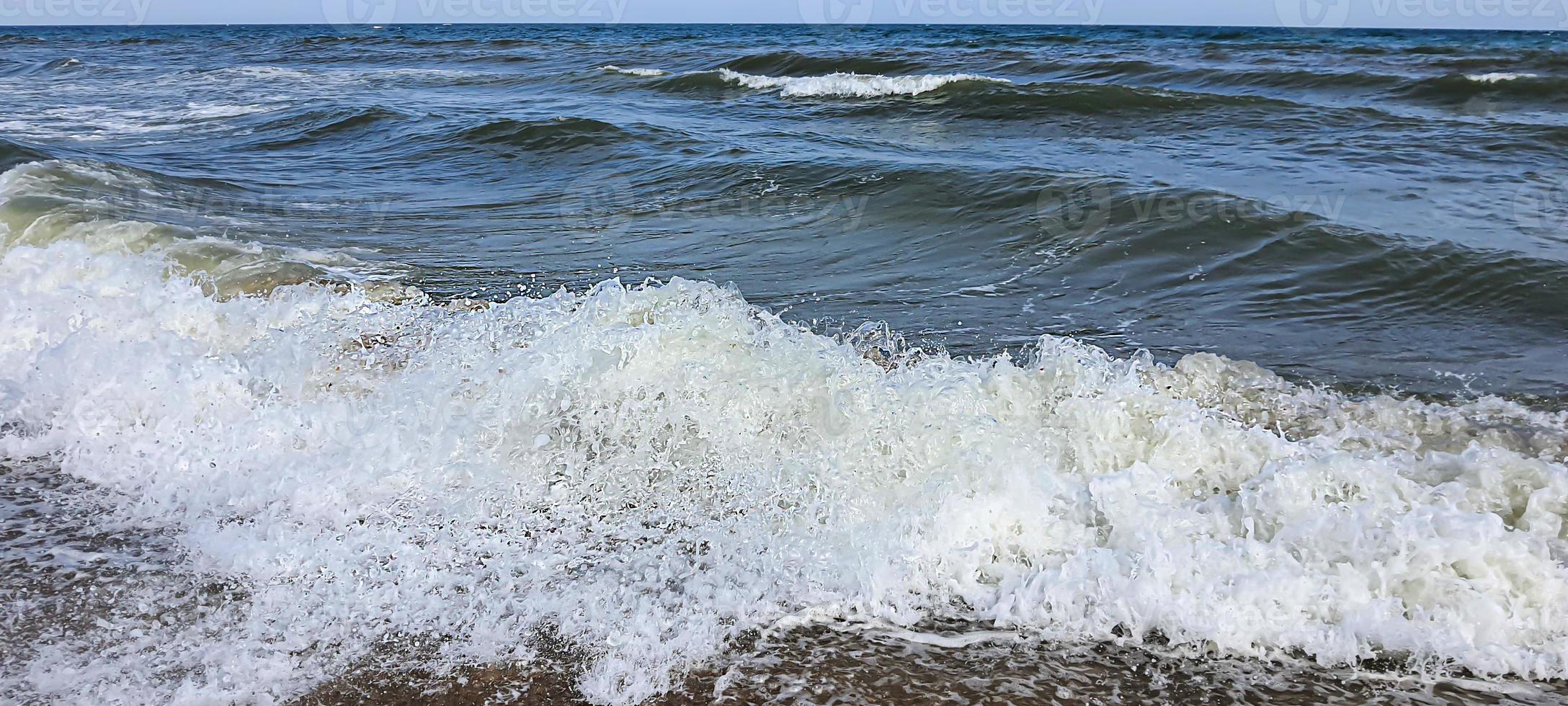 havslandskap. azurblå vattenfärg, vågor som skummar på stranden. foto
