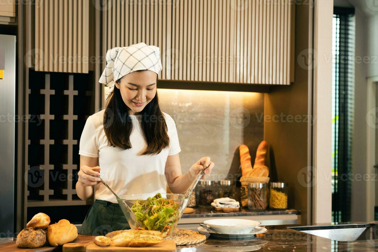 asiatisk hemmafru förbereder färska grönsaker för att göra sallad hemma köksbänk. foto