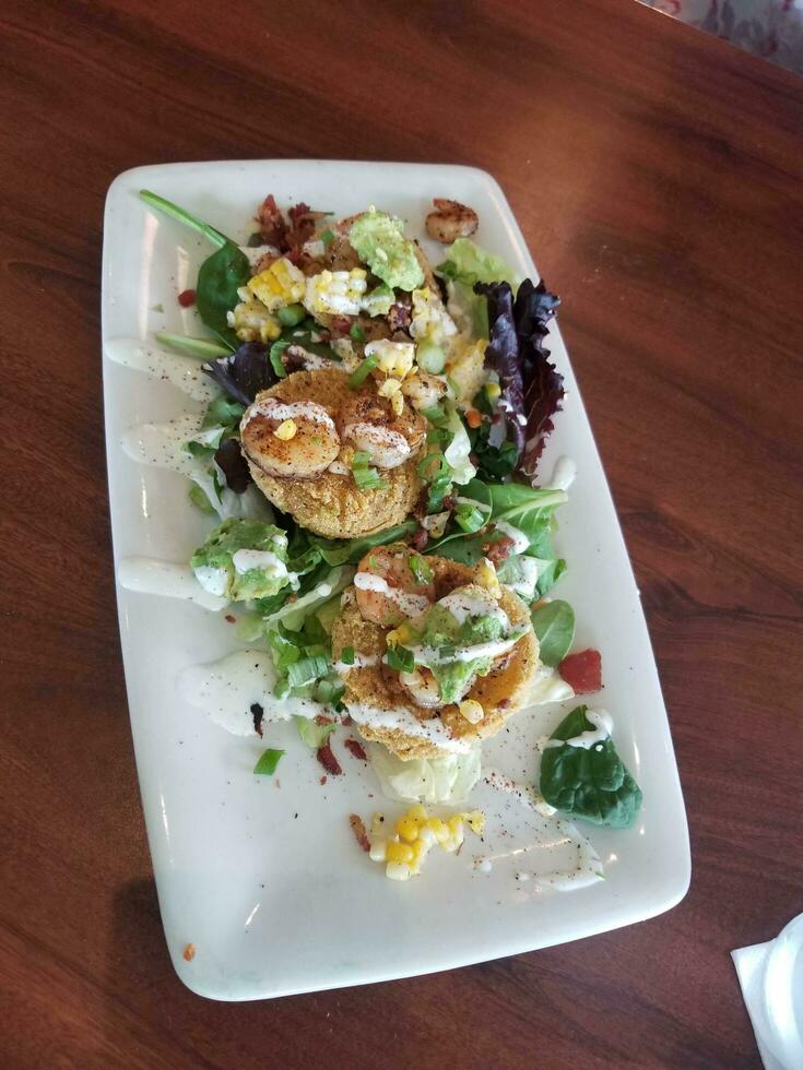 sallad med majs och ägg i en vit tallrik på en trä- tabell foto