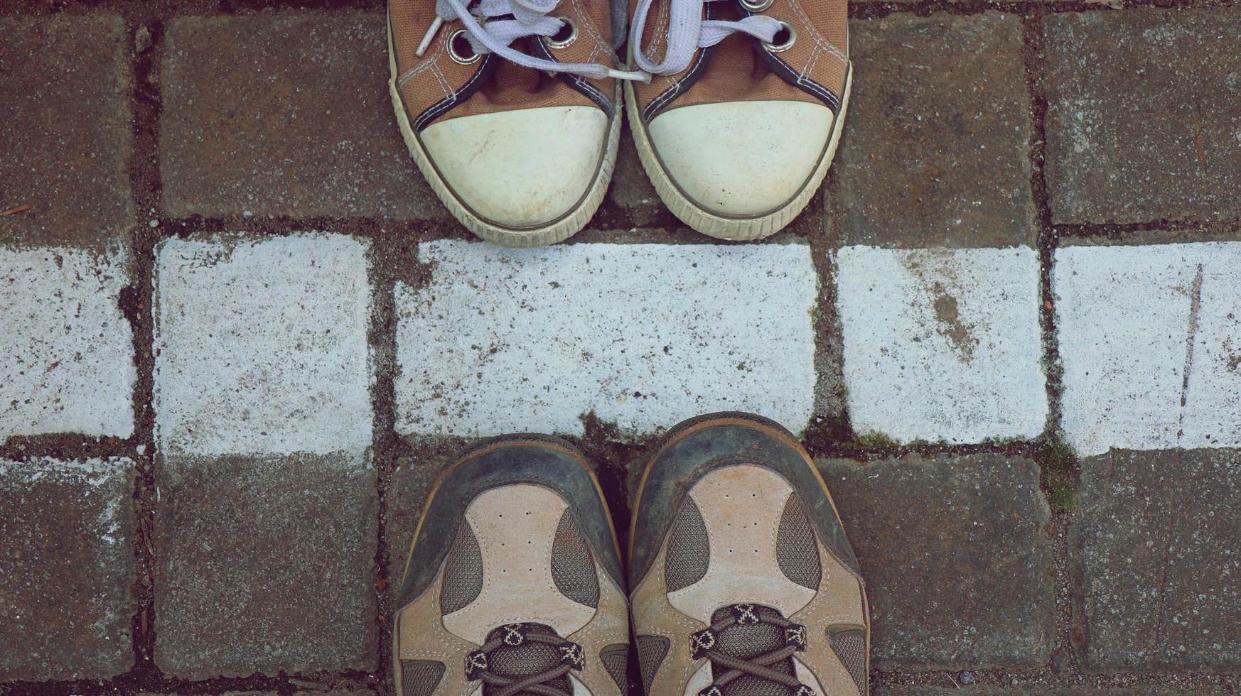 bruna sneakers och trailskor på asfalt, ovanifrån på vit linje foto