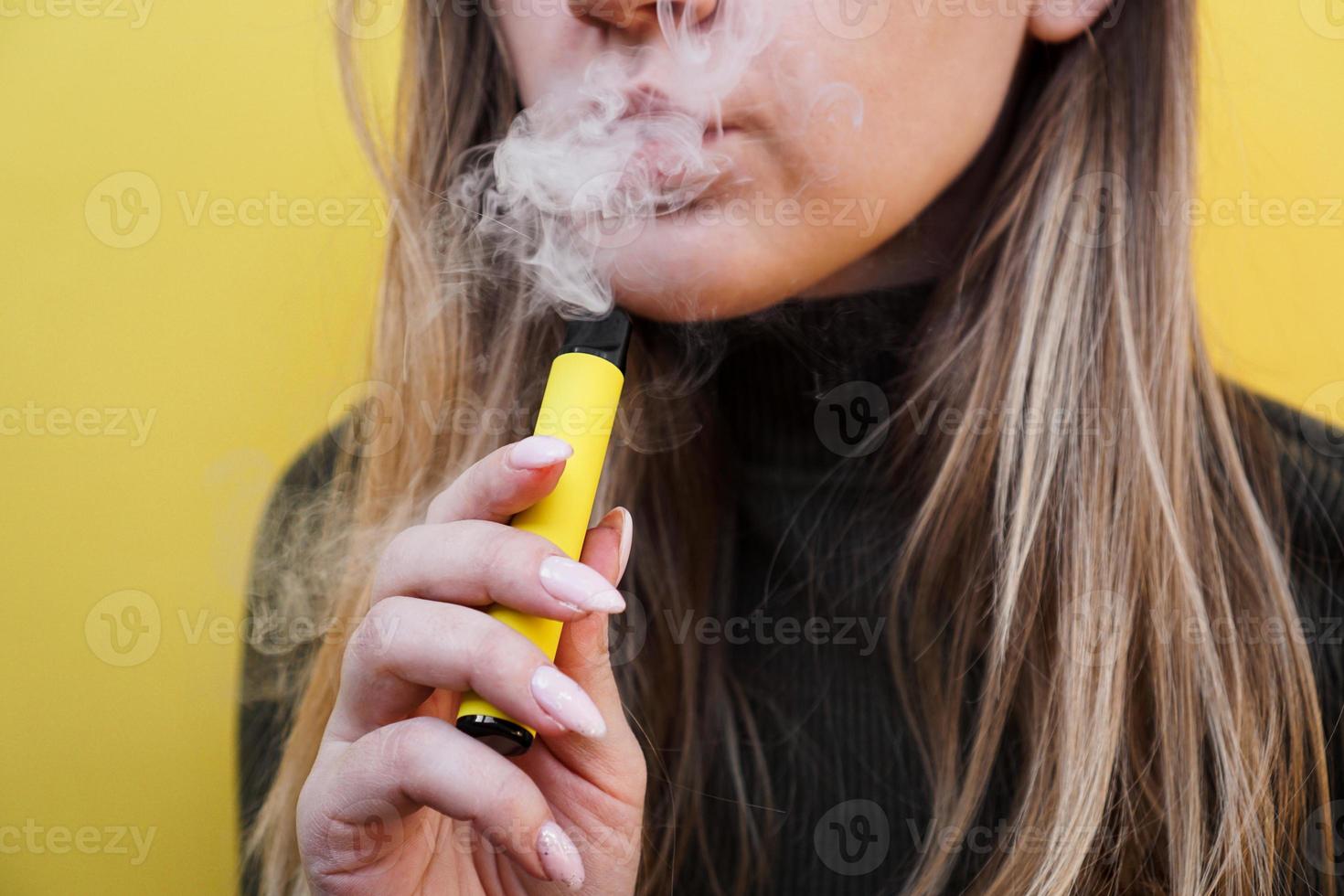 en ung flicka röker engångs elektronisk cigarett foto