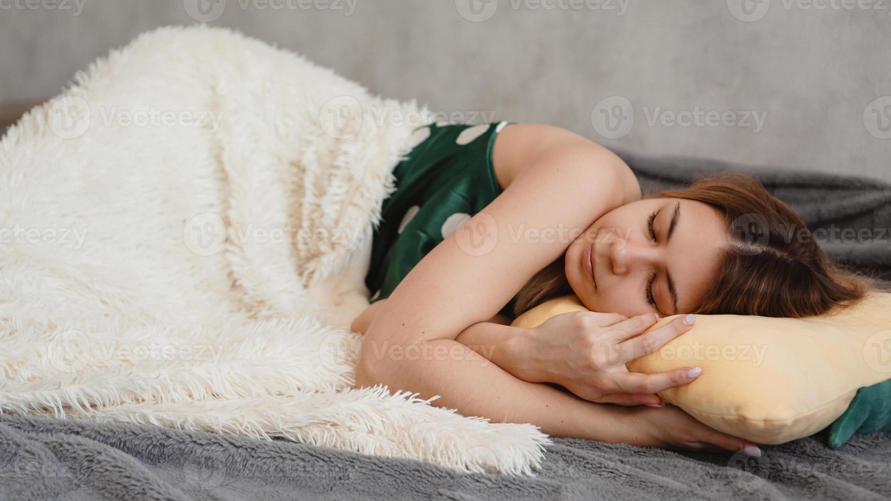 vacker ung flicka i en grön nattdräkt sover på en gul kudde foto