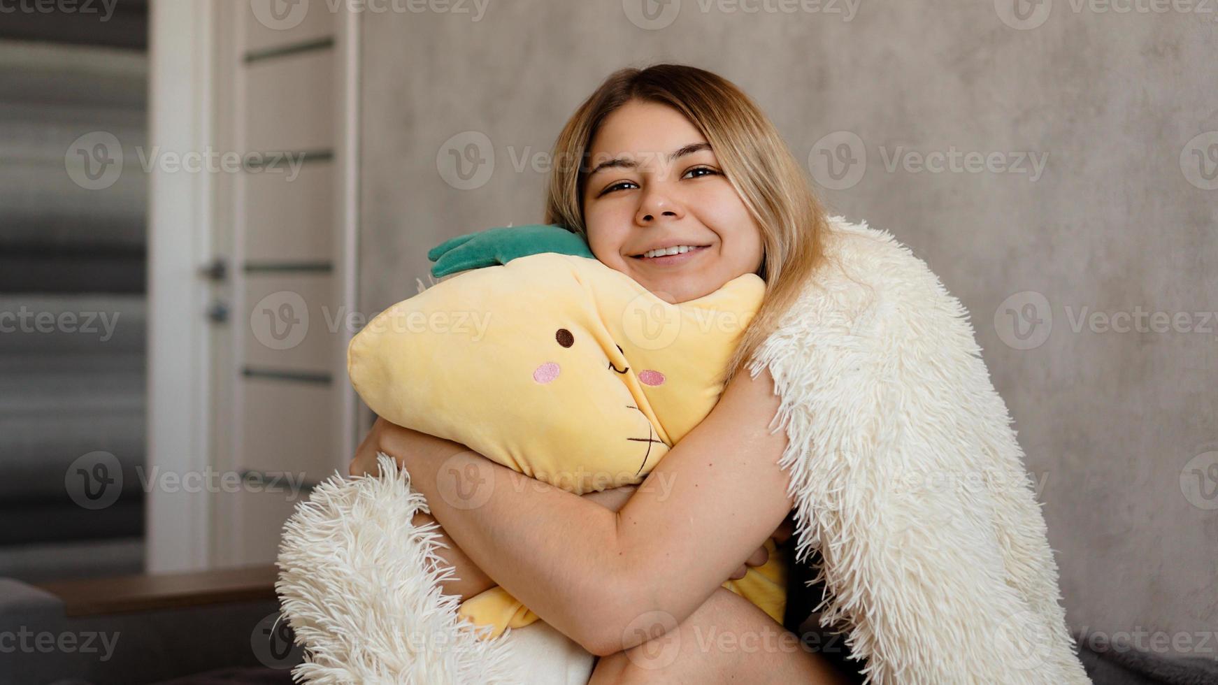 glad blondin på morgonen kramar en gul kudde. morgon koncept foto