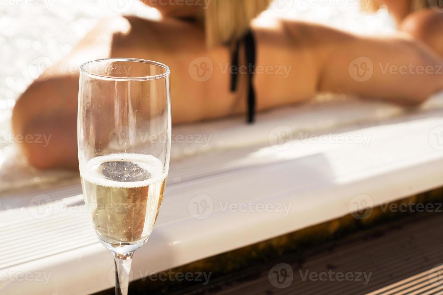 ett glas champagne vid poolen en solig dag. suddig bakgrund foto