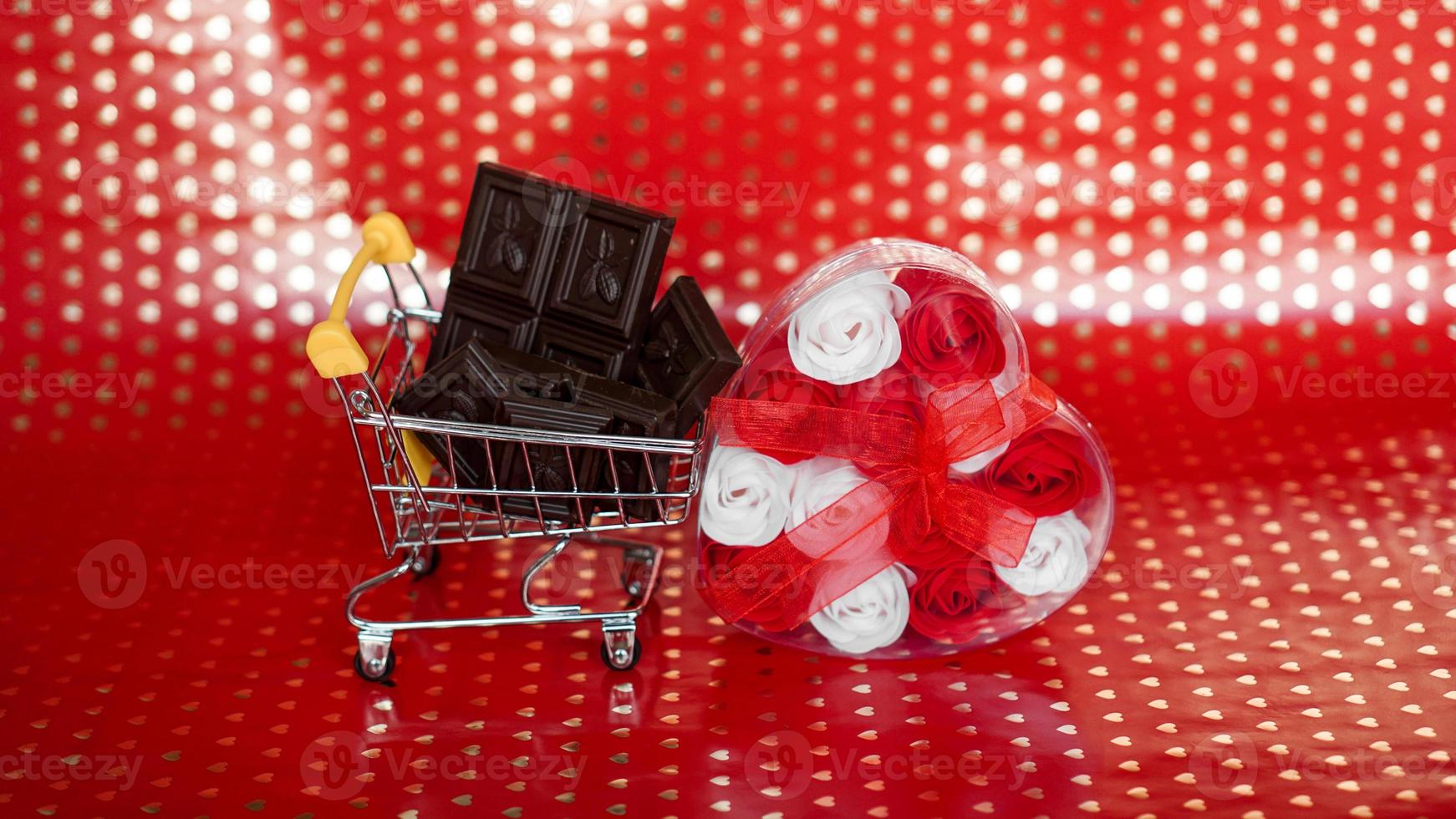 choklad i shoppingvagn och rosor på rött foto