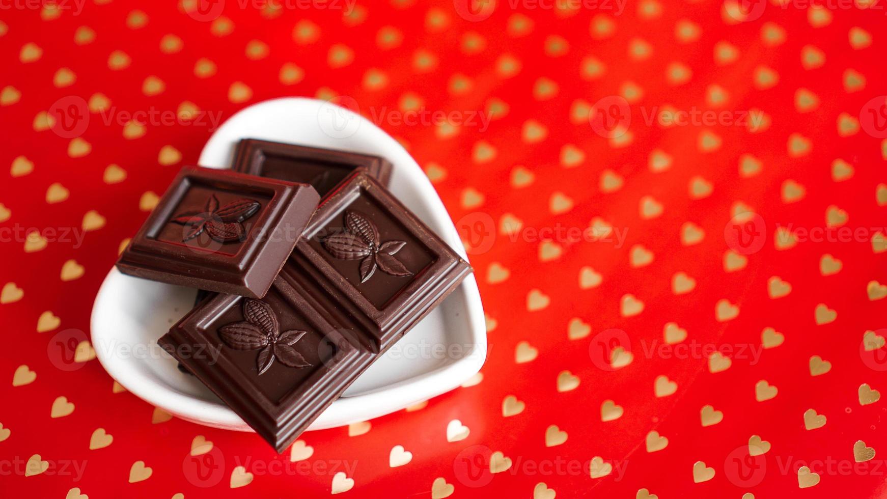 choklad i en hjärtformad tallrik på röd bakgrund foto