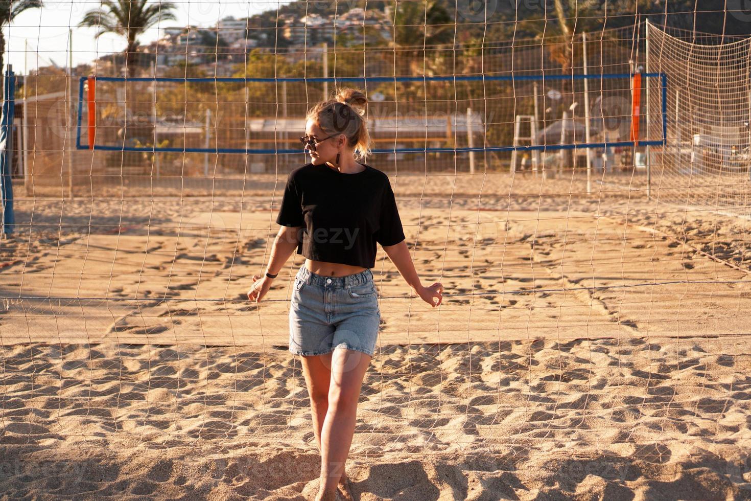 porträtt av attraktiv kvinna nära volleybollnät på stranden foto