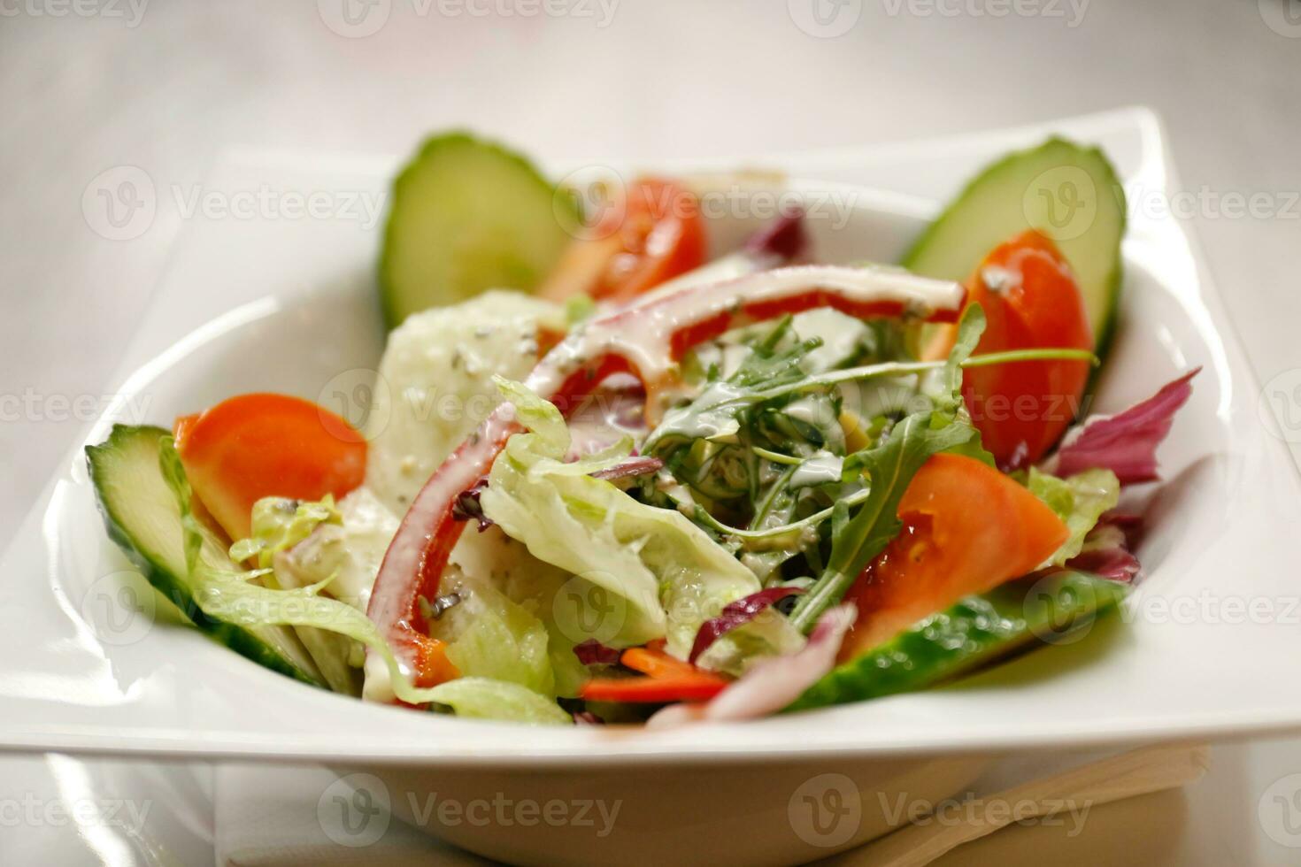 sallad med gurka, tomat och ost på en vit tallrik foto