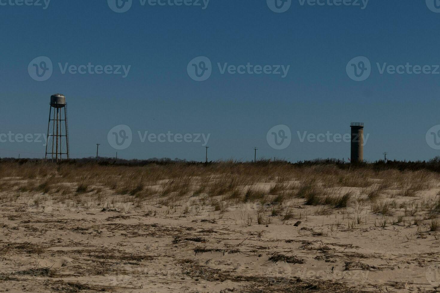 solnedgång strand i cape Maj ny jersey. de sand är en Söt brun. de sanddyner som visar grön lång gräs till hjälp förhindra erosion. där är en se upp torn i de distans som väl som en vatten torn. foto