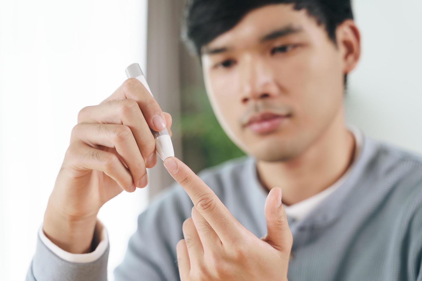 man använder lansett på finger som kontrollerar blodsockernivån med glukosmätare. foto