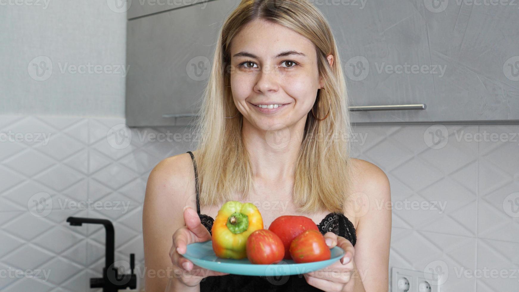 kvinna som håller tallrik med färska grönsaker och ler foto