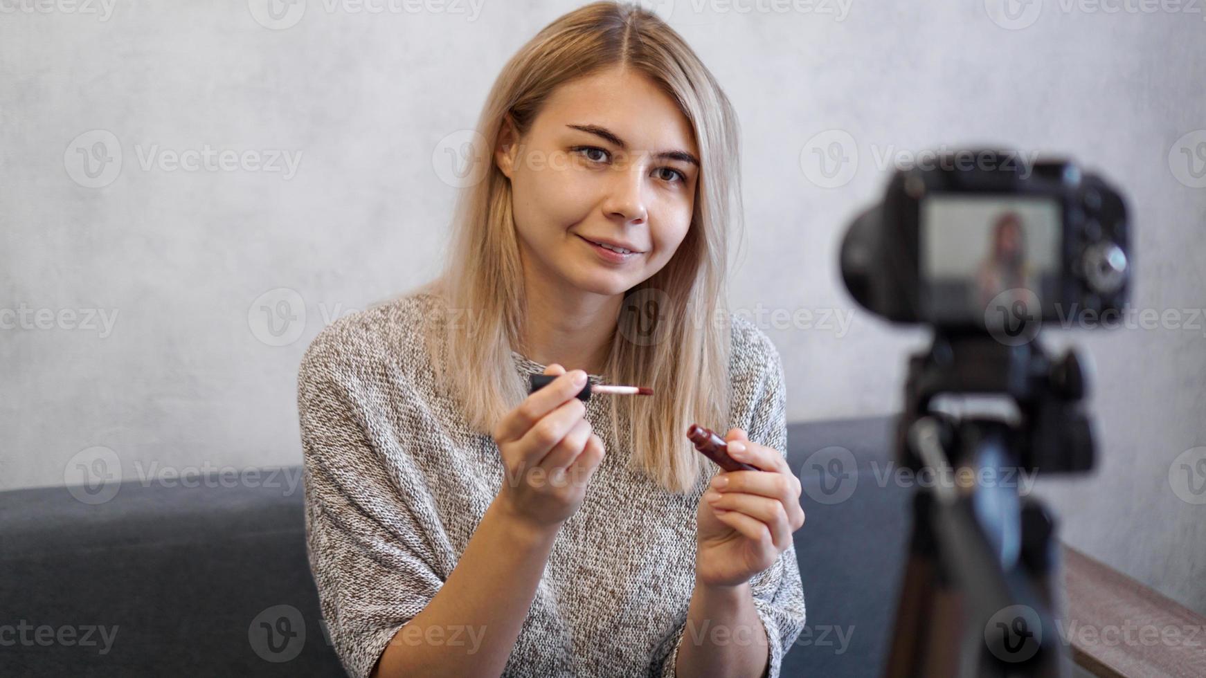 vloggerhona som visar läppstift. skönhetsbloggare i hemmastudion foto