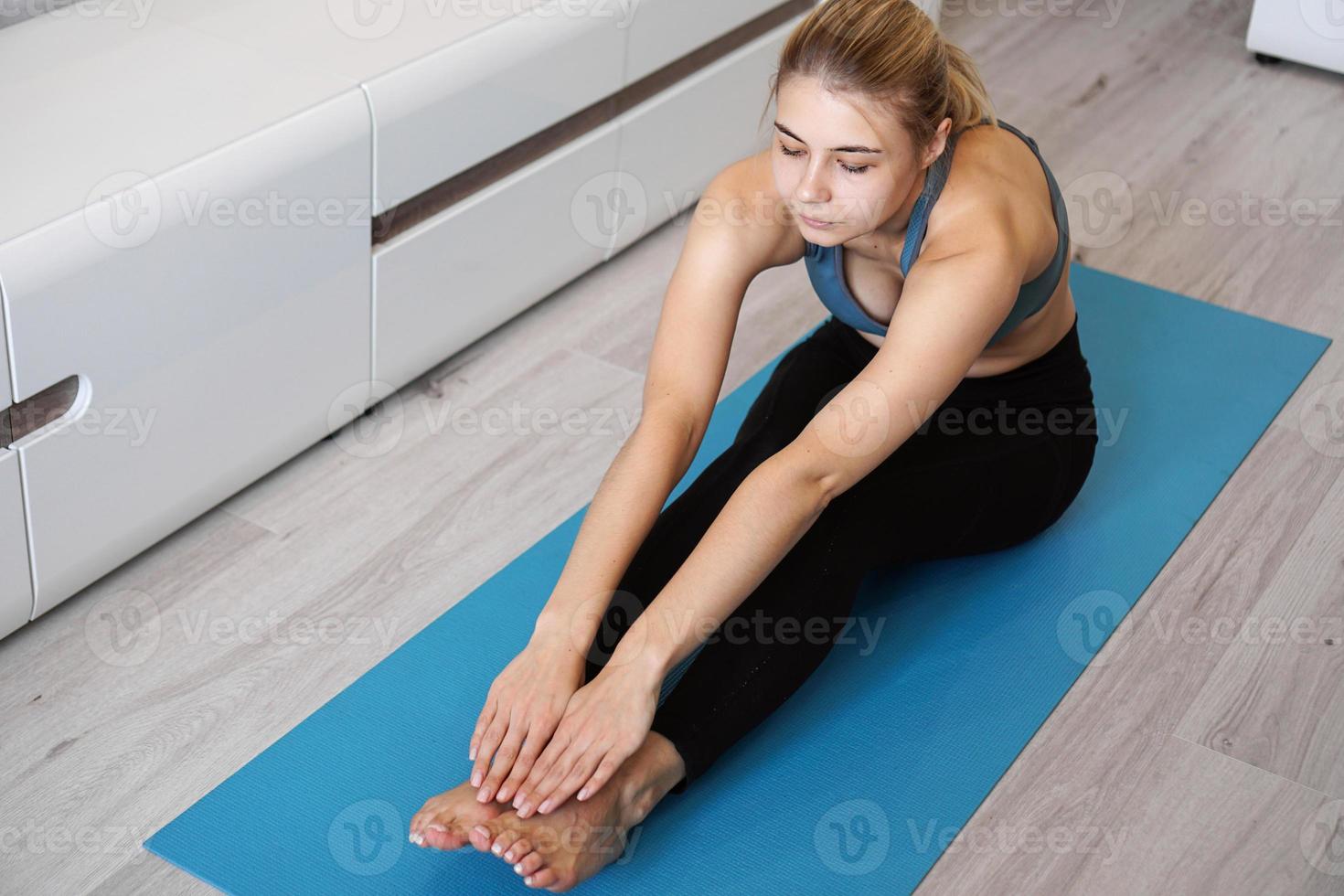 fitness kvinna som sträcker benen hemma foto