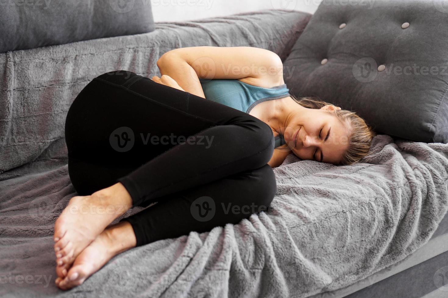 efter träningen. trevlig ung kvinna som sover på soffan foto