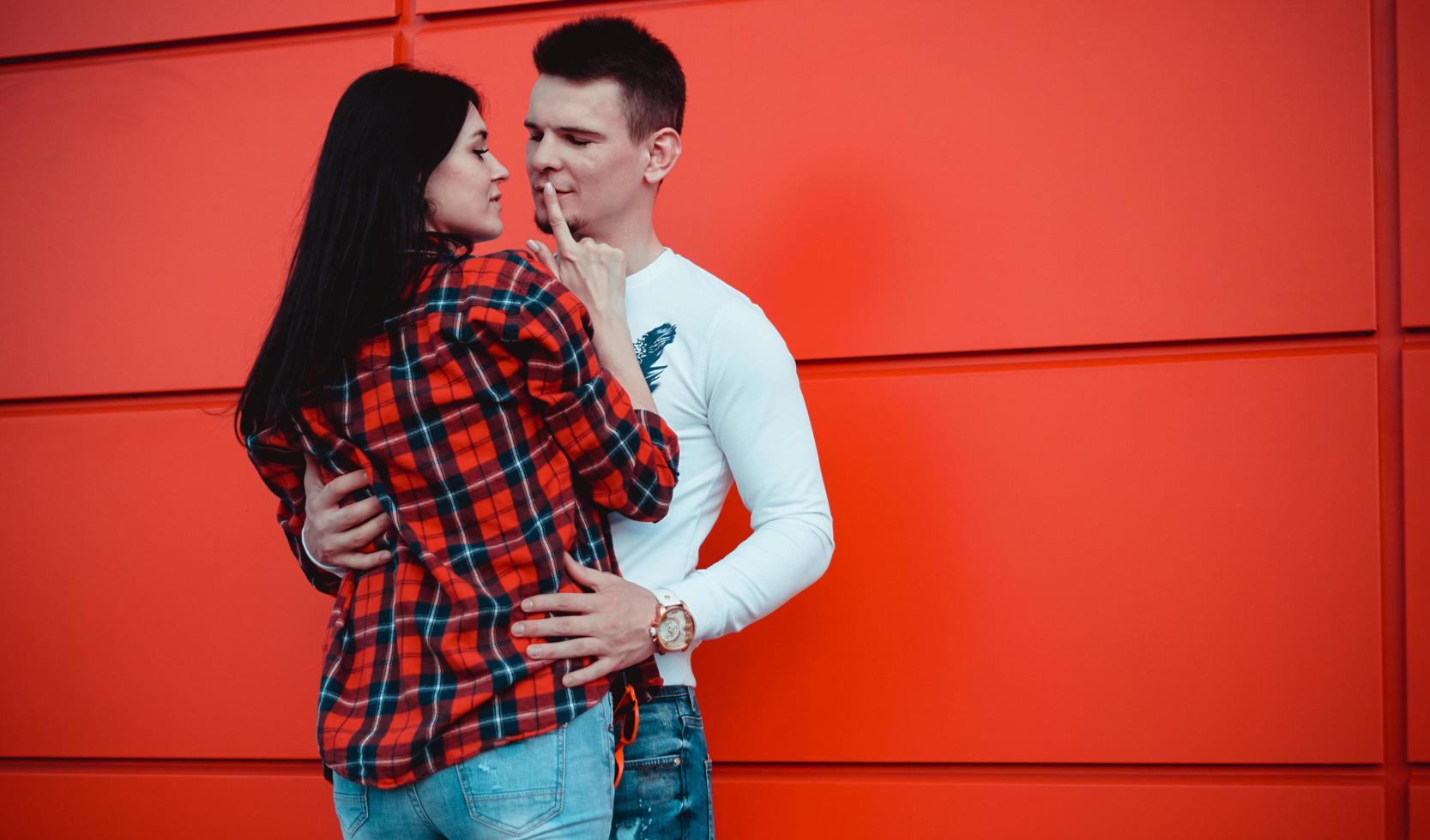par dejtar och kramas förälskade i en solig dag - röd bakgrund foto