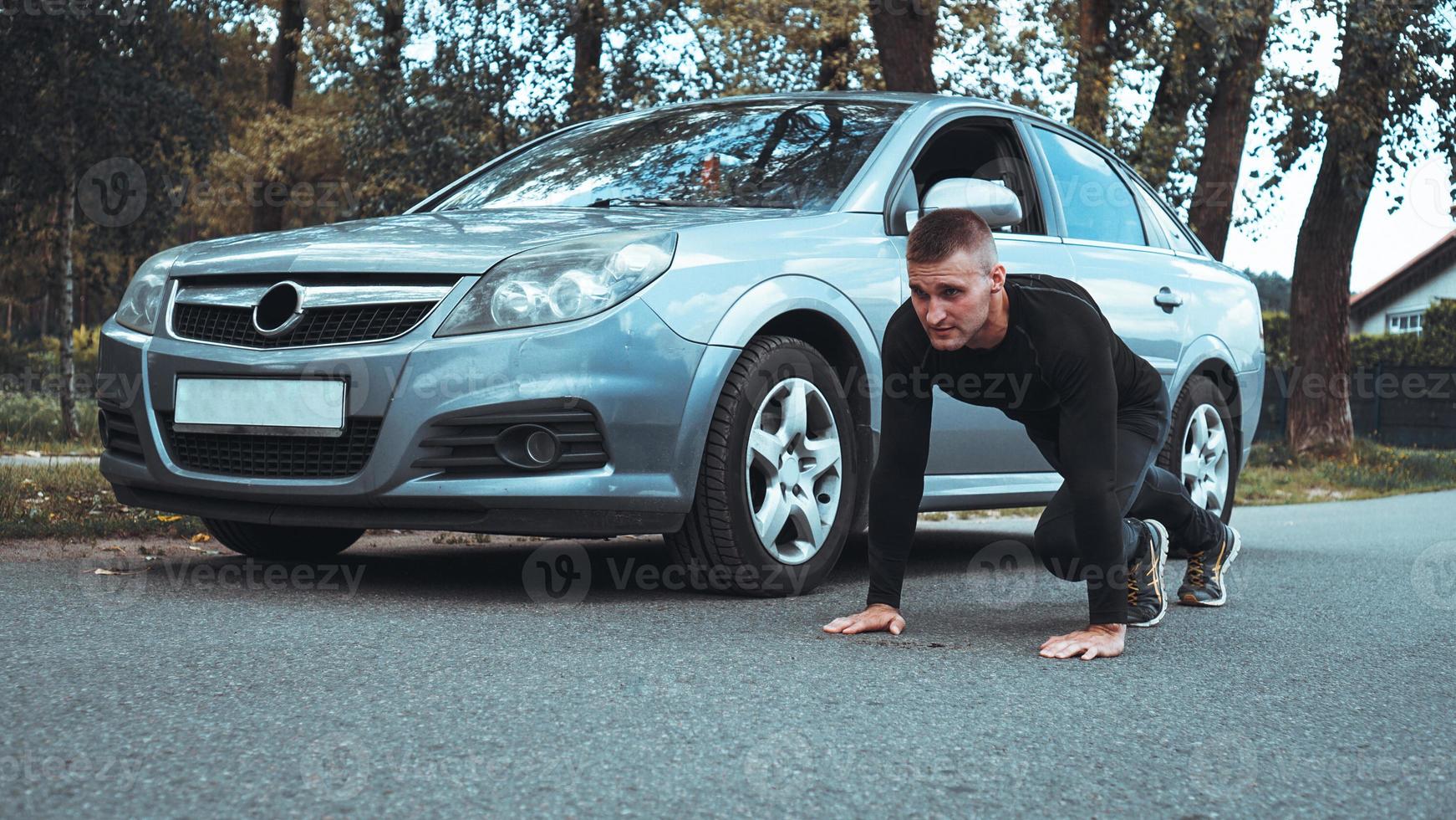 stilig man nära bilen. idrottaren vred ut bredvid maskinen foto