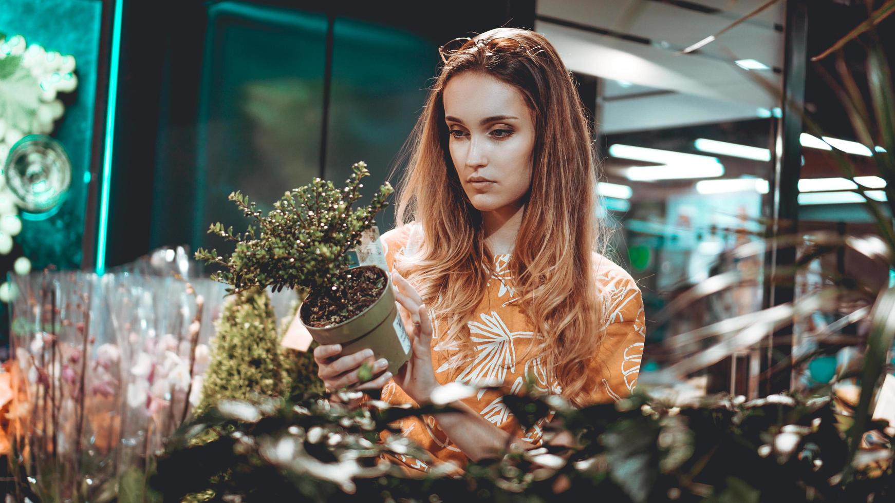 ung kvinna som köper blommor på ett trädgårdscenter foto