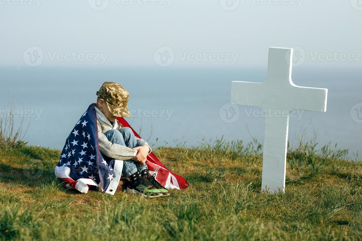 en ung pojke i en militärmössa, täckt av USA: s flagga foto