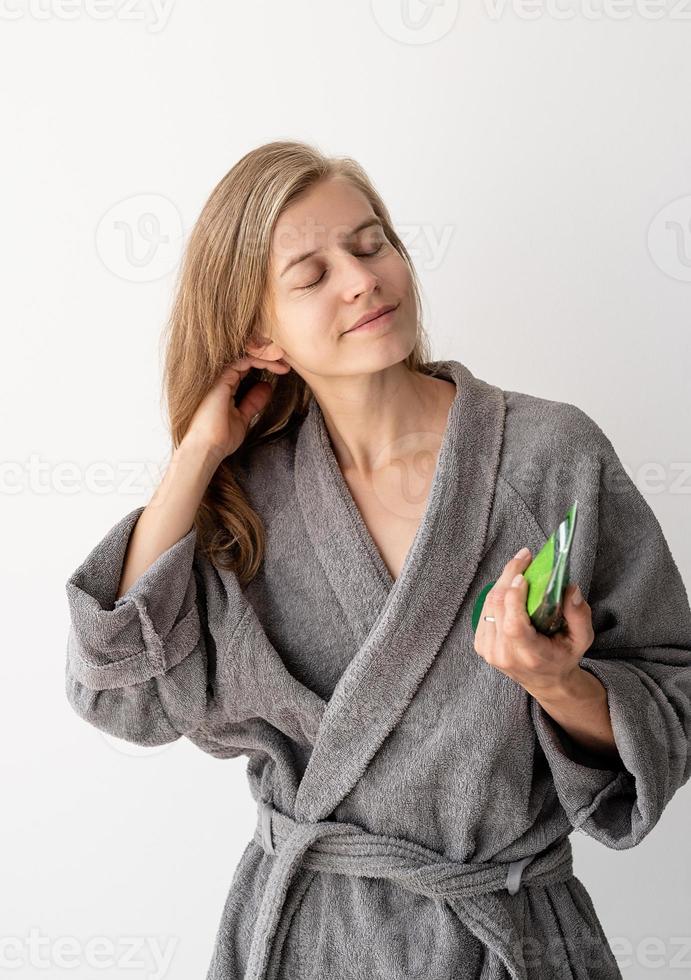 glad ung kvinna som applicerar hårmask i badrummet foto