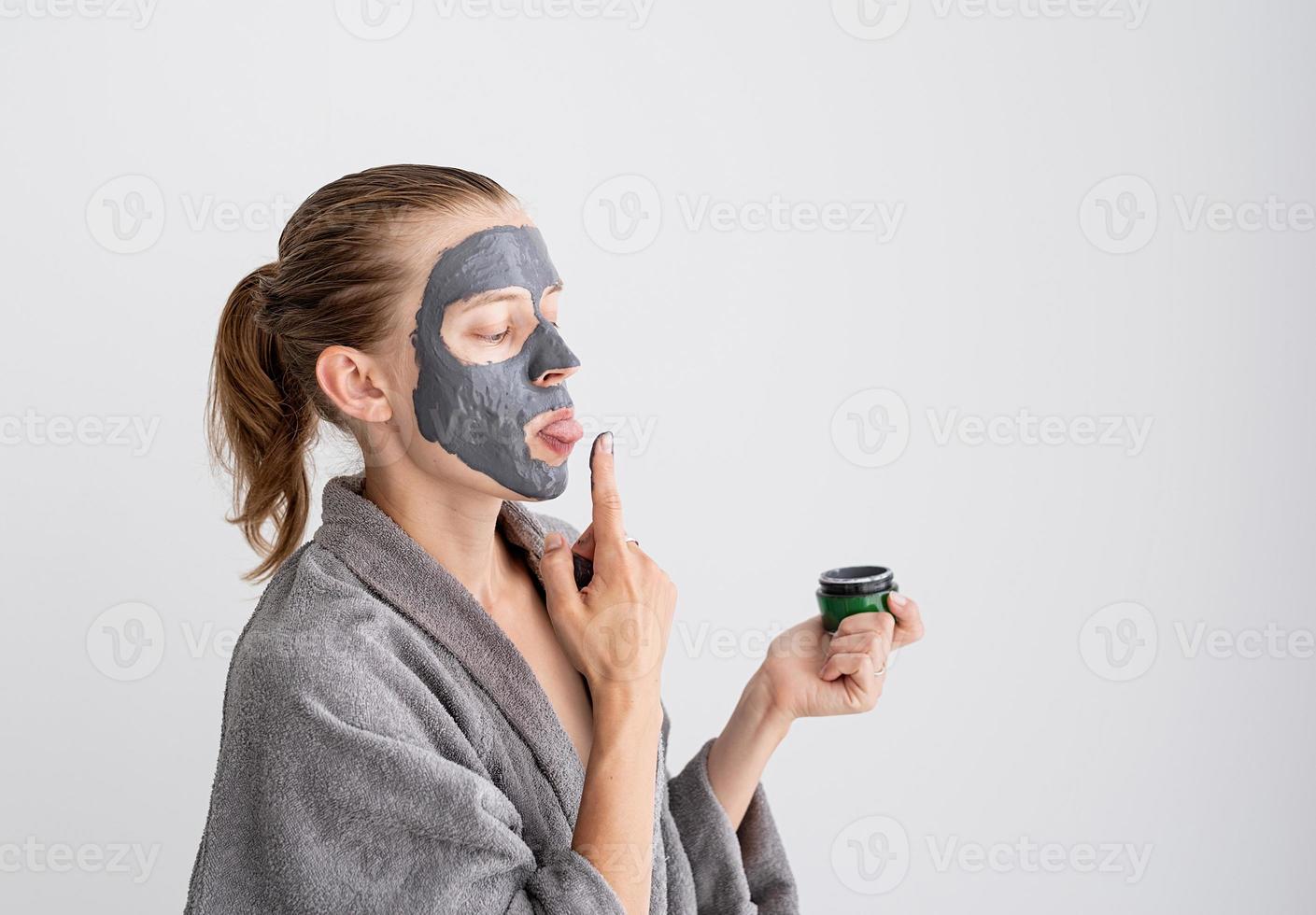 glad rolig kvinna som applicerar ansiktsmask och provar det foto