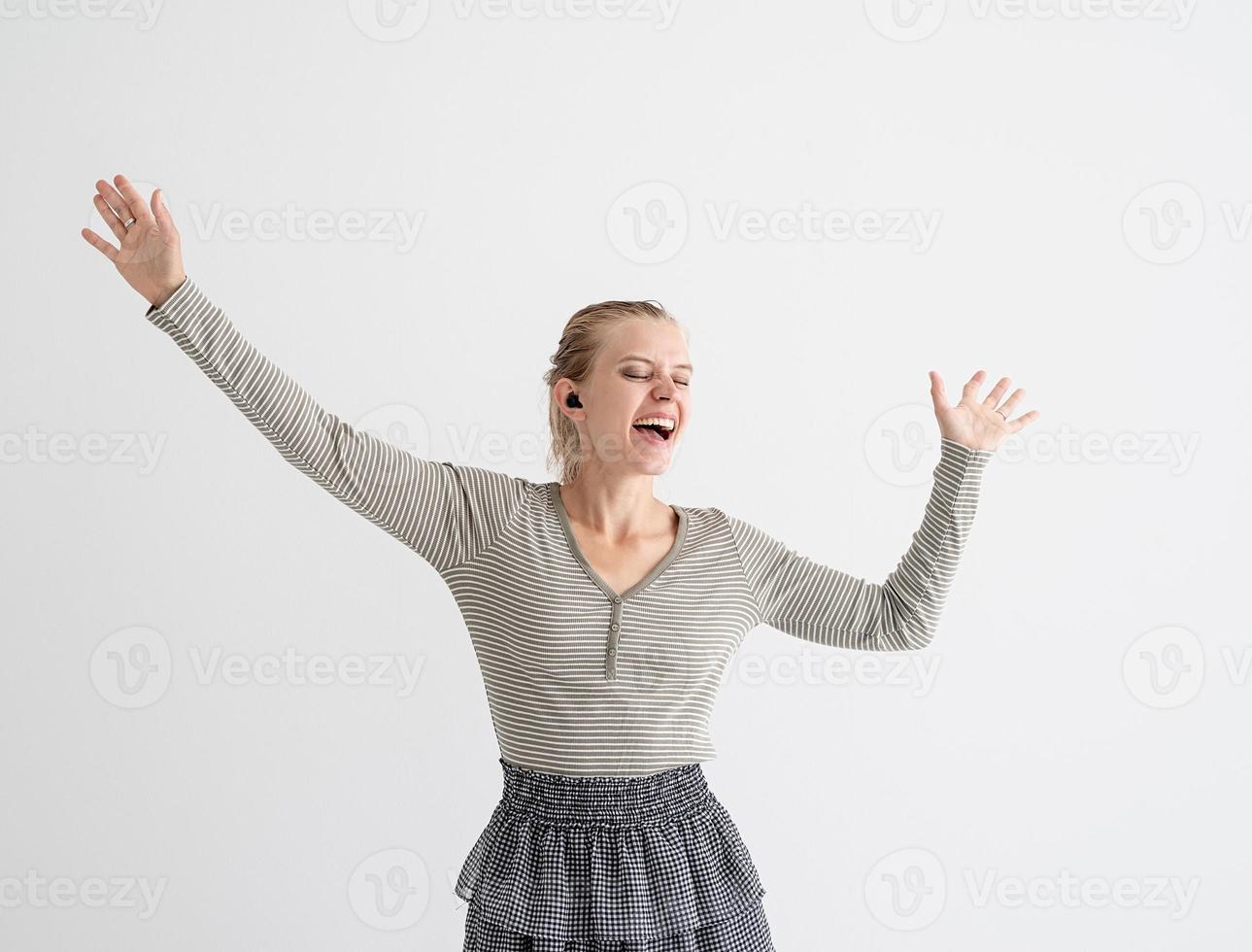 ung kvinna som håller trådlösa hörlurar och dansar foto