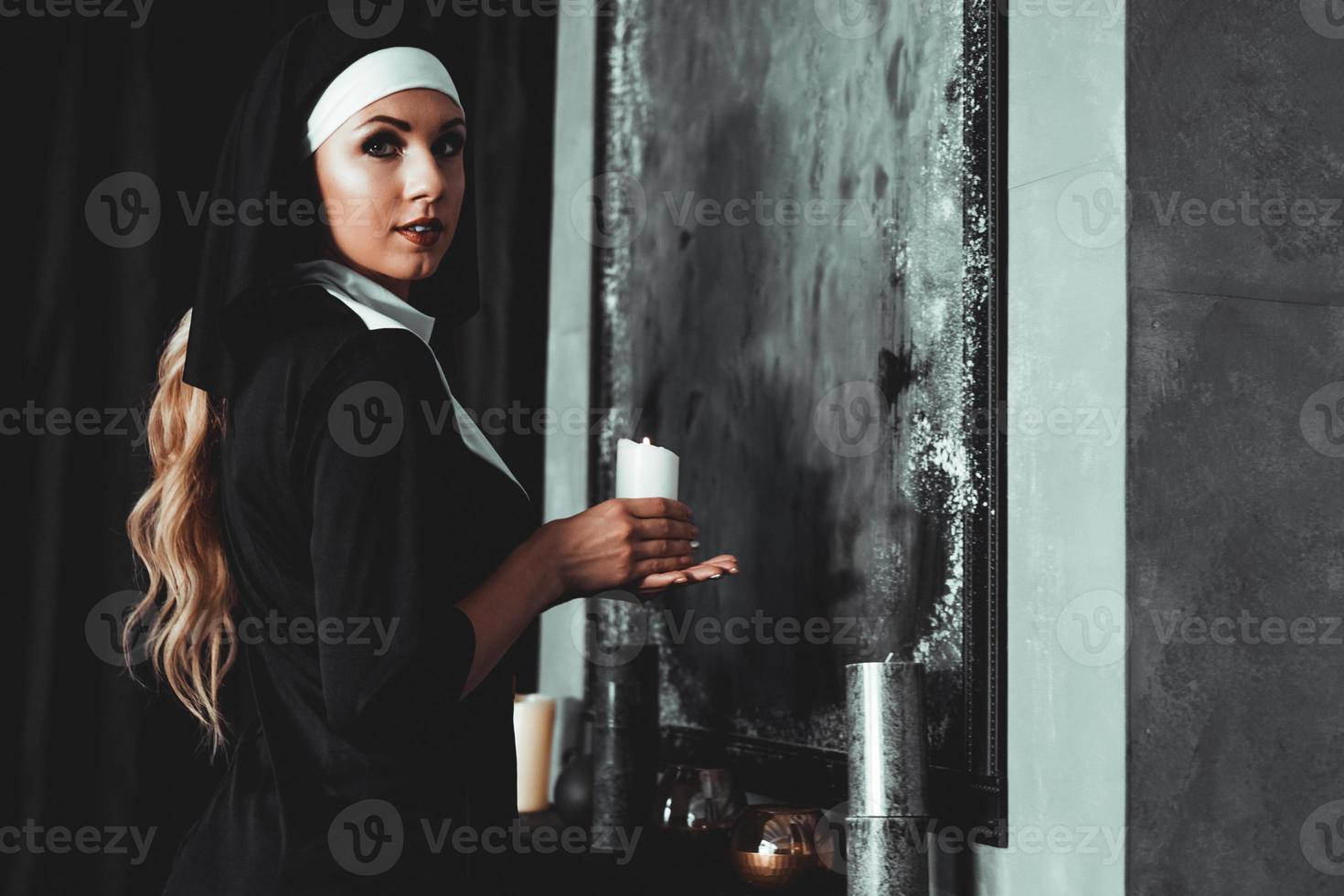 ung katolsk nunna håller ljus i sina händer foto