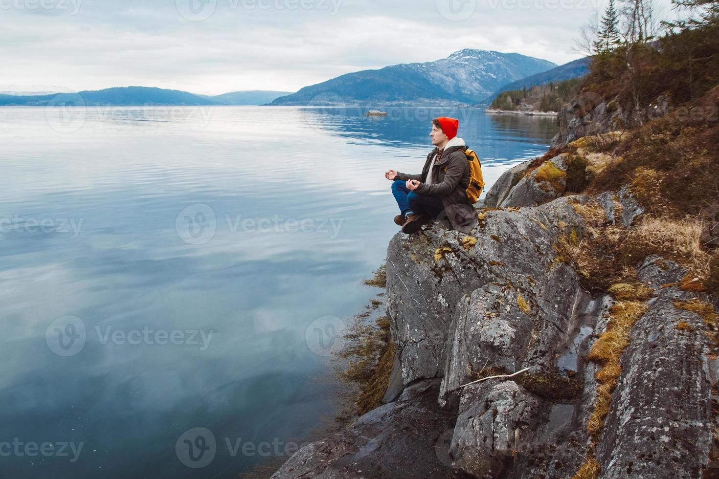 resenär man i en meditativ position sitter på en stenig strand foto