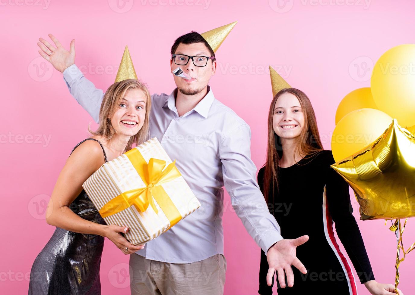 porträtt av glada vänner som firar födelsedagsfest, rosa bakgrund foto