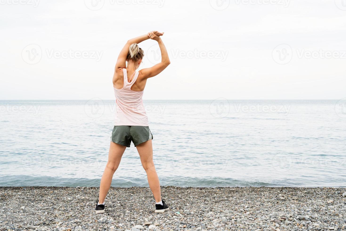 blong idrottare kvinna gör övningar på stranden foto