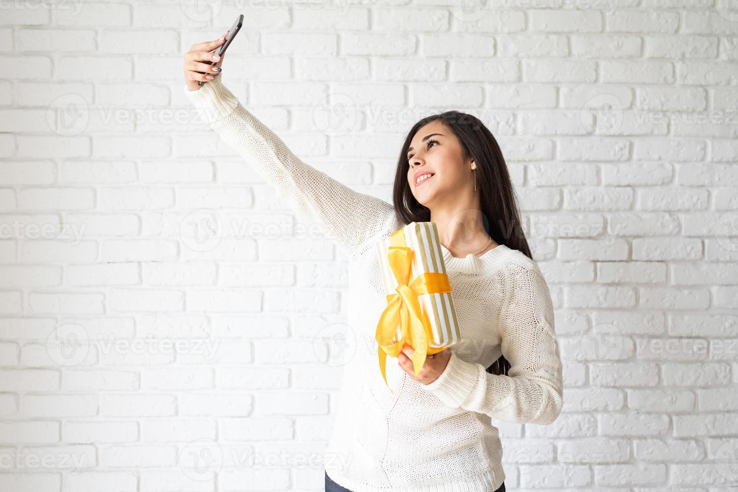 kvinna som håller en presentask och tar selfie foto