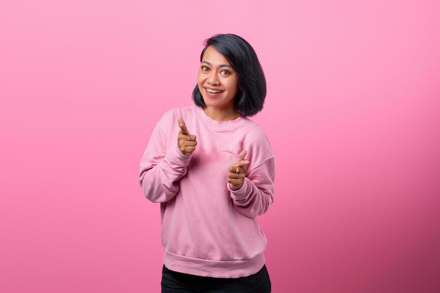glad ung asiatisk kvinna som pekar fingrar mot kameran foto
