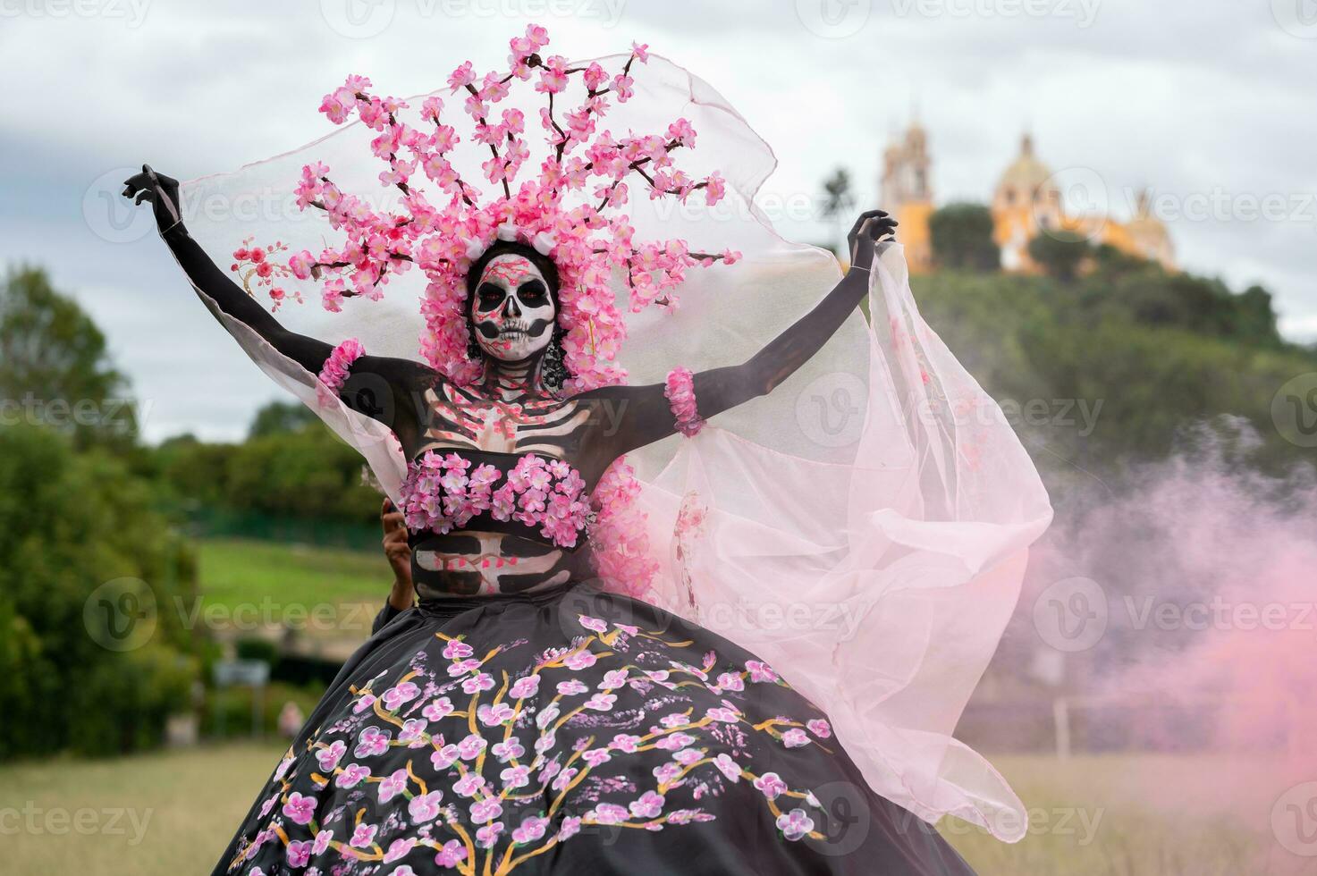 förtjusande catrina en dia de los muertos fotografering i cholulas cempasuchil fält, inramade förbi de ikoniska kolula kyrka fira skönhet tradition och de förtjusande rosa rök foto