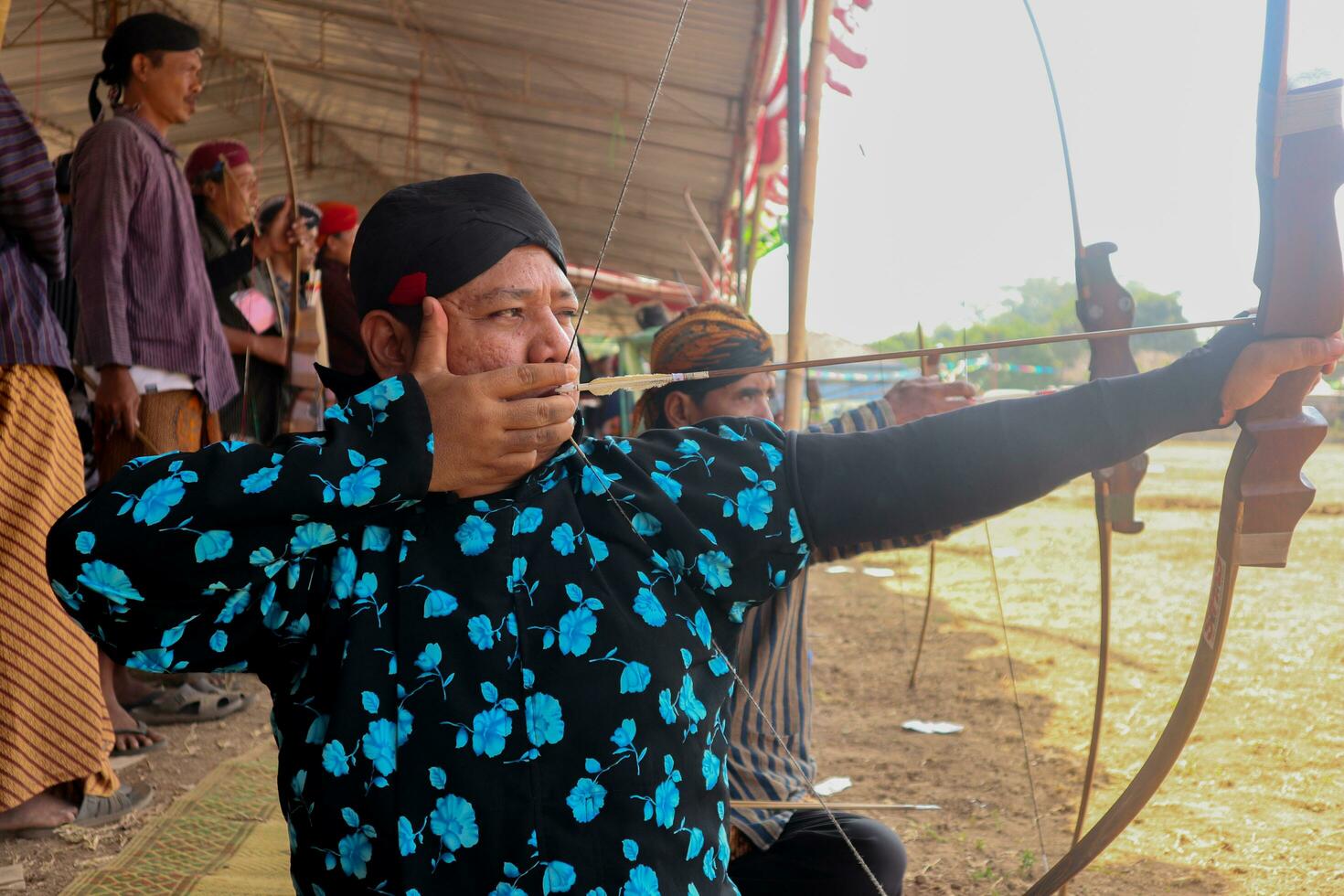 klaten, Indonesien, augusti 15, 2023. manlig och kvinna deltagare, klädd i javanese beställnings- drog hans rosett förbi vindögd till uppnå koncentration av mål noggrannhet i traditionell javanese pil trad. foto