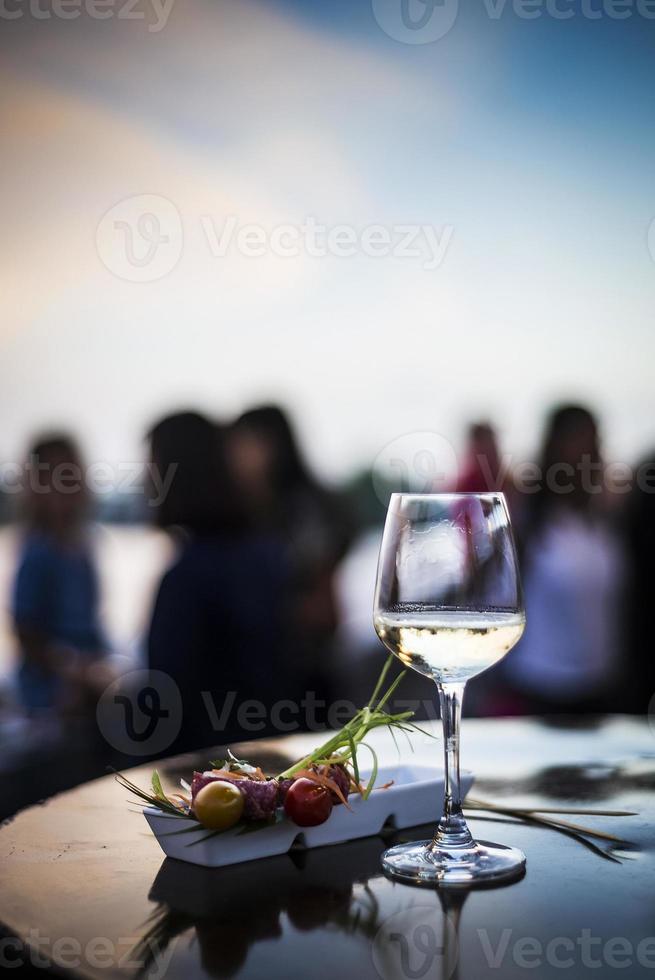 glas vitt vin med gourmetmat tapasnacks i utomhusbaren vid solnedgången foto